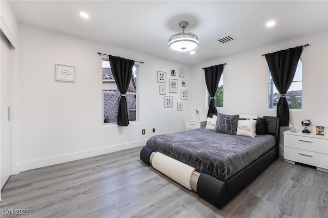 bedroom featuring multiple windows, wood finished floors, visible vents, and baseboards