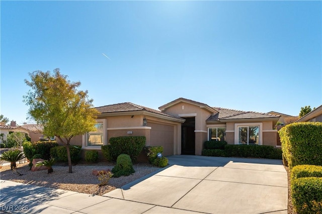 view of front of home featuring driveway, an attached garage, and stucco siding