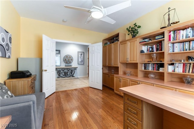 home office with light wood-type flooring and ceiling fan