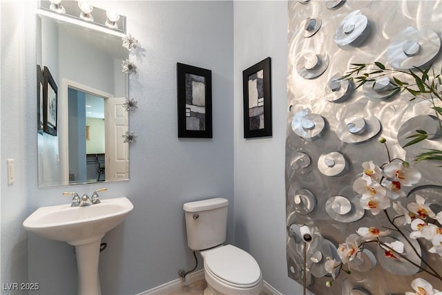 bathroom with toilet, baseboards, and a sink