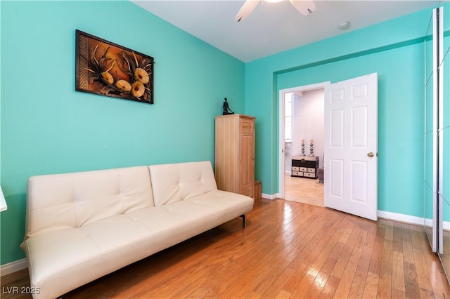 sitting room with a ceiling fan, hardwood / wood-style flooring, and baseboards