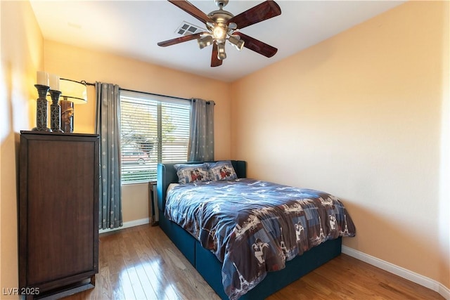 bedroom with visible vents, baseboards, and wood finished floors