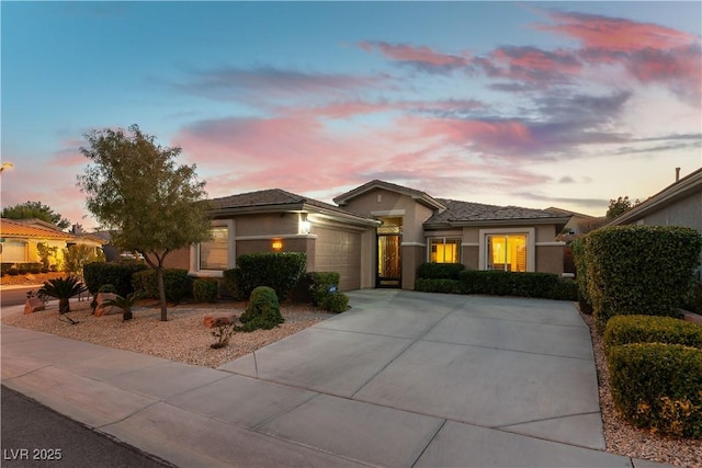 prairie-style home with a garage, concrete driveway, and stucco siding