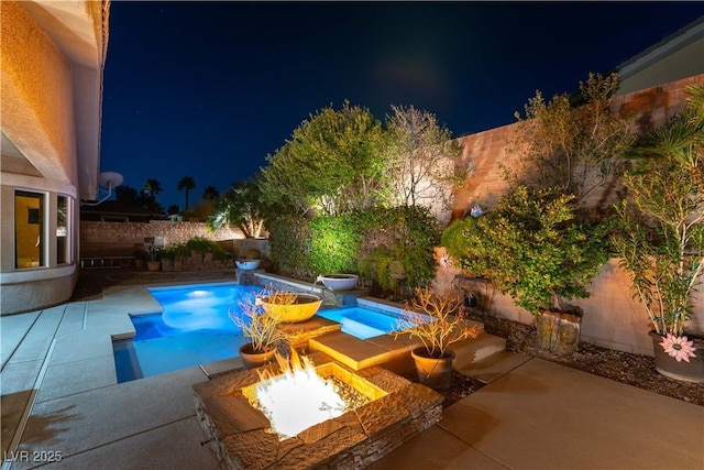 pool at night with a patio area, a fenced backyard, a fire pit, and a fenced in pool