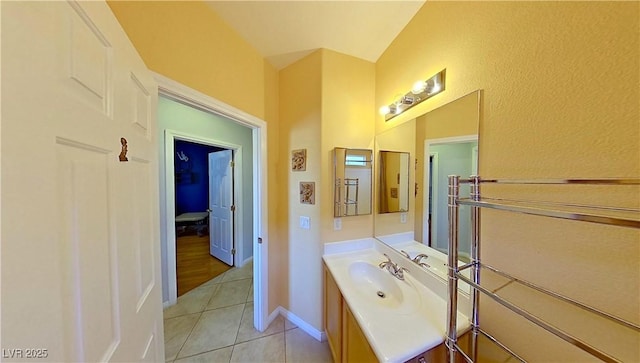 bathroom featuring tile patterned flooring, vaulted ceiling, vanity, and baseboards