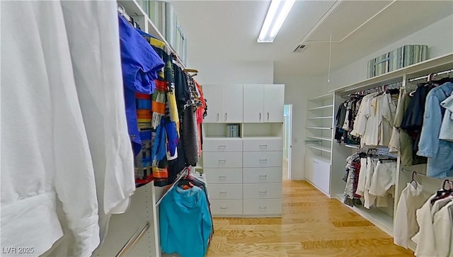 spacious closet with visible vents, light wood finished floors, and attic access