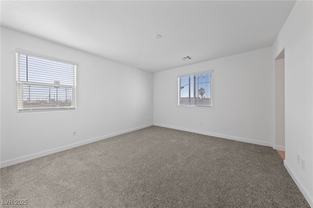 carpeted spare room with plenty of natural light, visible vents, and baseboards