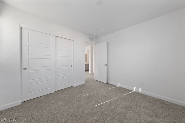 unfurnished bedroom featuring carpet floors, a closet, visible vents, and baseboards