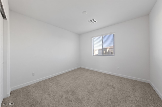 spare room featuring carpet, visible vents, and baseboards