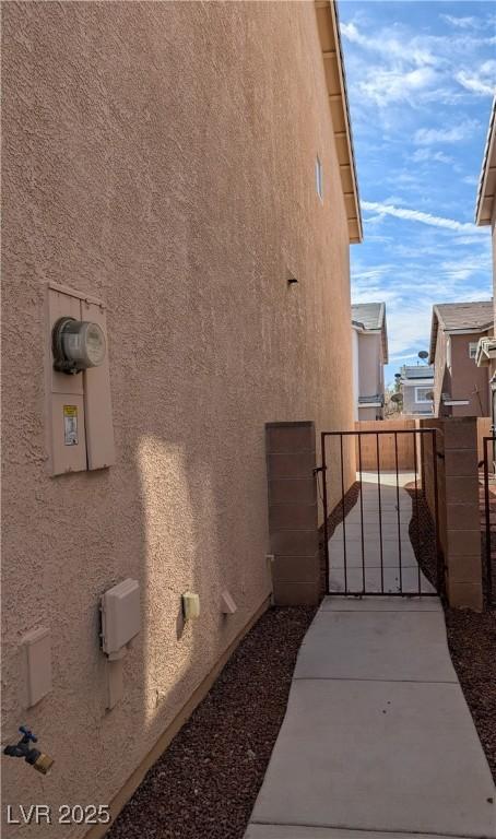 view of side of home with a gate, fence, and stucco siding