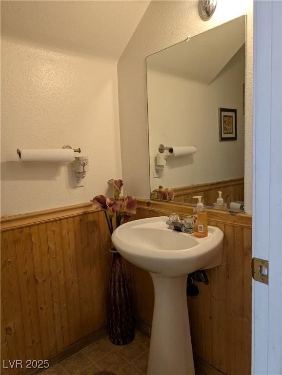 bathroom featuring vaulted ceiling, wainscoting, tile patterned floors, and wooden walls