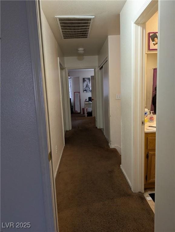 corridor featuring carpet floors, baseboards, and visible vents