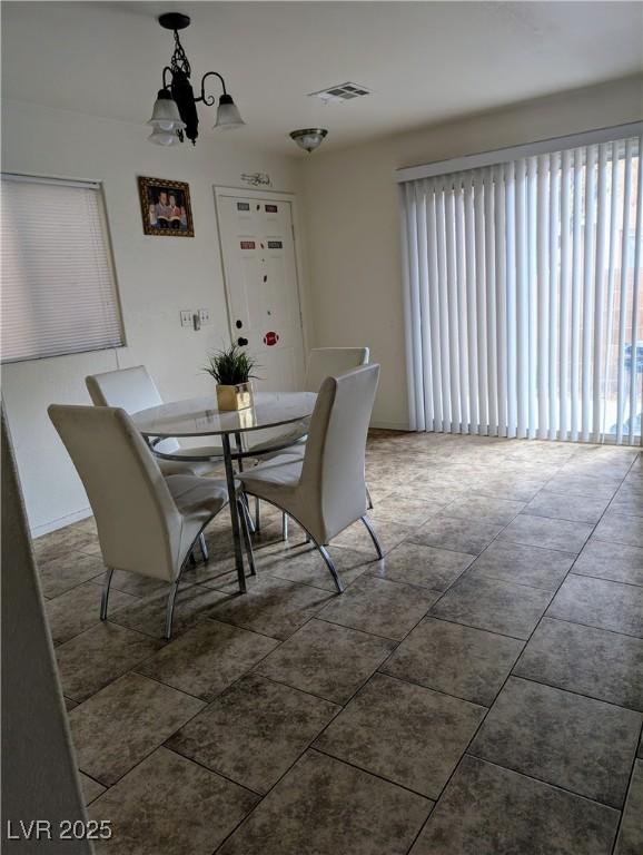 tiled dining room featuring a chandelier and visible vents