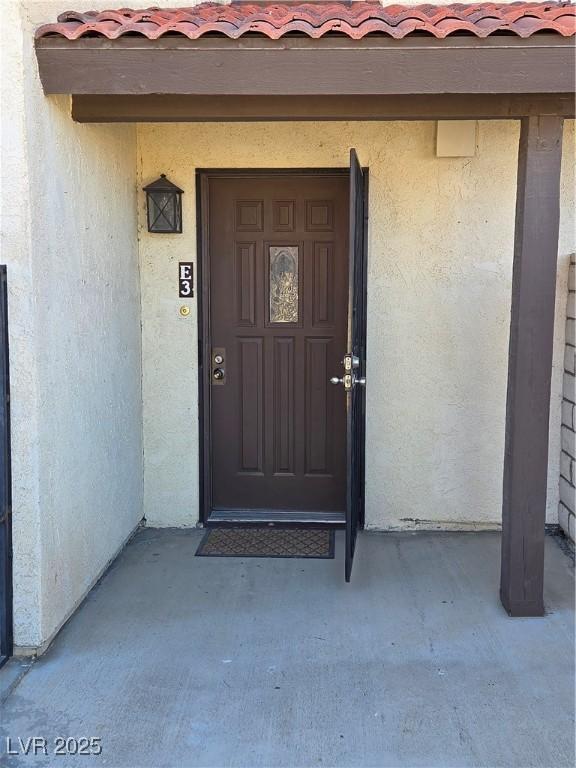 property entrance featuring a tiled roof and stucco siding