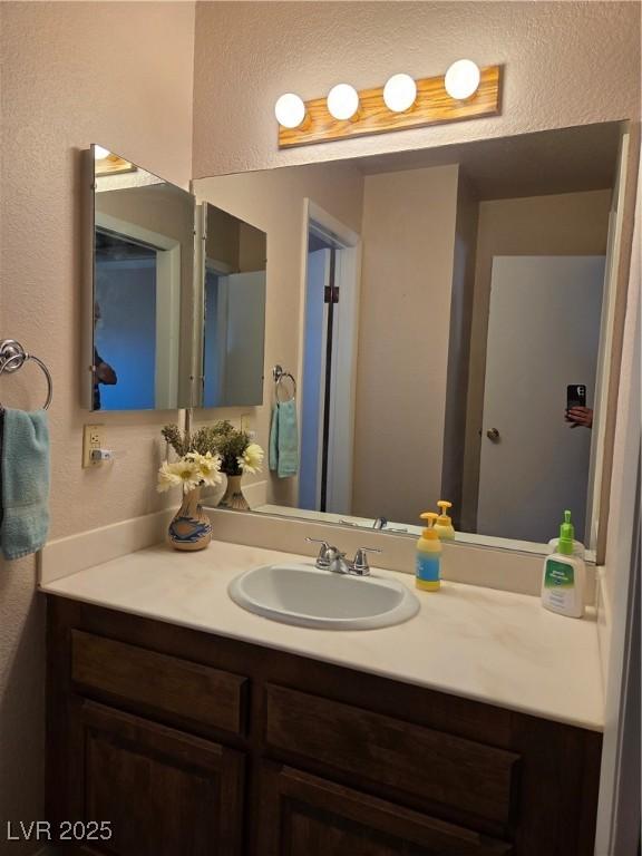 bathroom with a textured wall and vanity