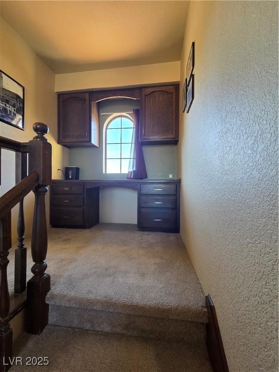 unfurnished office with carpet and a textured wall