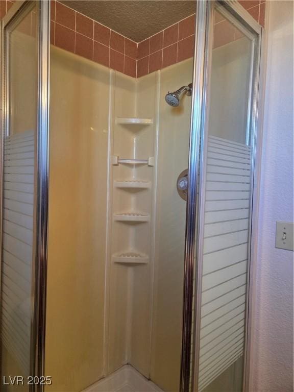 bathroom with a stall shower and a textured ceiling