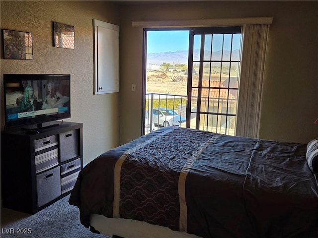 bedroom featuring access to outside, carpet flooring, and a textured wall