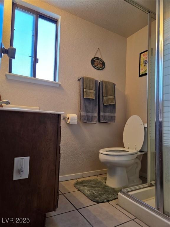 full bath with toilet, a stall shower, vanity, tile patterned flooring, and baseboards