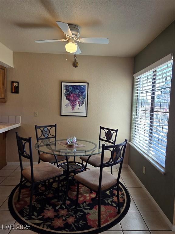 dining space featuring light tile patterned floors, plenty of natural light, a ceiling fan, and a textured ceiling