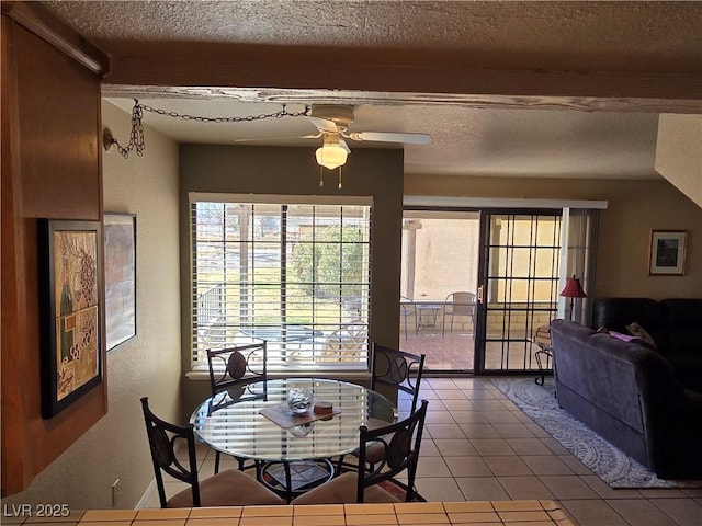 tiled dining room with a ceiling fan, a textured wall, and a textured ceiling