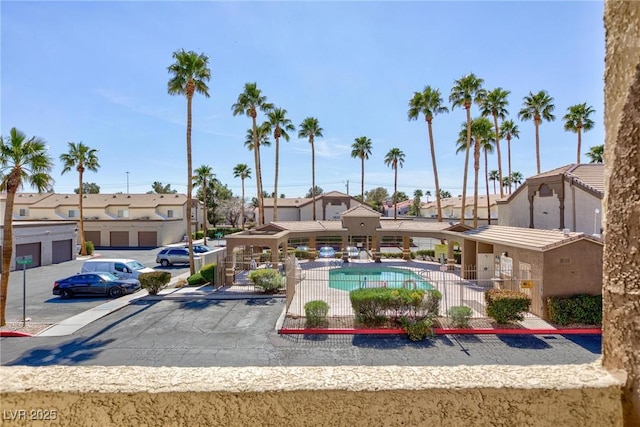 view of community featuring a swimming pool, uncovered parking, a residential view, and fence