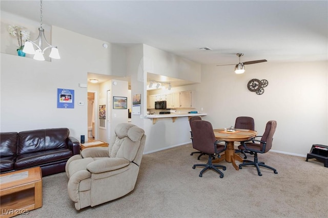 interior space featuring light colored carpet, visible vents, vaulted ceiling, baseboards, and ceiling fan with notable chandelier