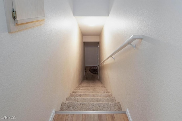 staircase with a textured wall and wood finished floors