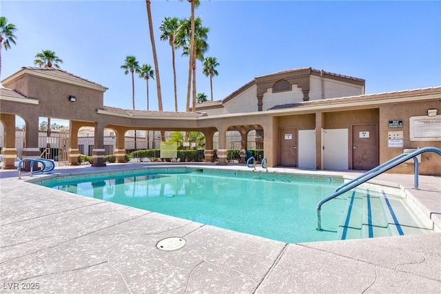 community pool with a patio area and fence