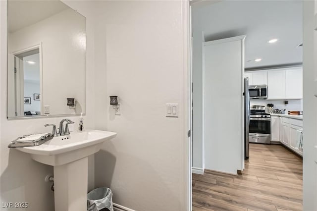 bathroom with a sink, wood finished floors, and recessed lighting