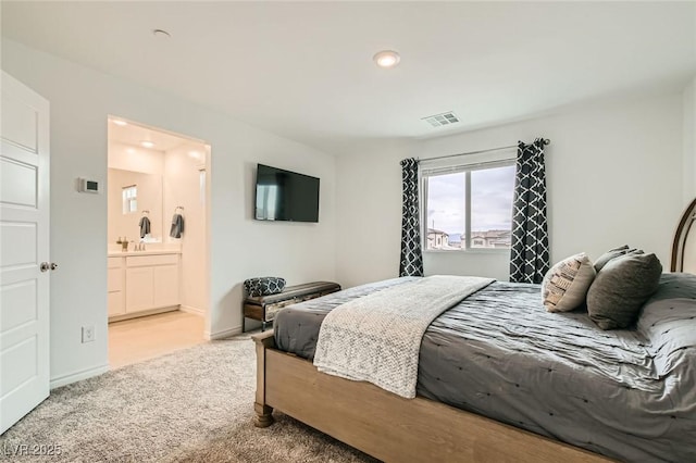 carpeted bedroom with ensuite bath, visible vents, and baseboards