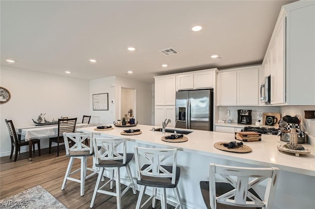 kitchen with stainless steel appliances, light countertops, visible vents, white cabinets, and a sink