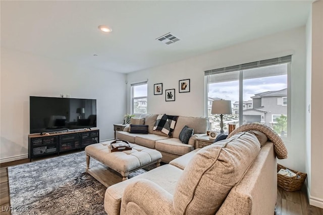 living room featuring visible vents, baseboards, and wood finished floors