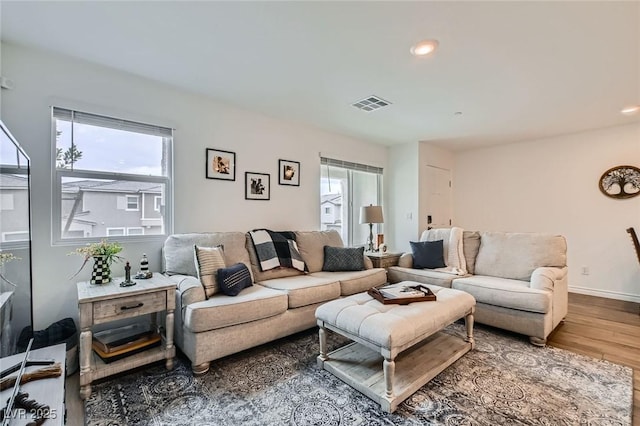 living area with a healthy amount of sunlight, visible vents, wood finished floors, and recessed lighting