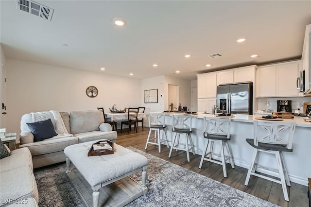 living room featuring wood finished floors, visible vents, and recessed lighting