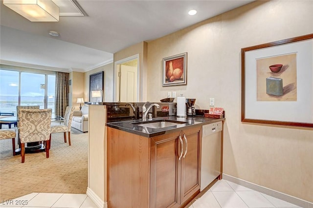 kitchen featuring dark stone countertops, a peninsula, white dishwasher, a sink, and open floor plan