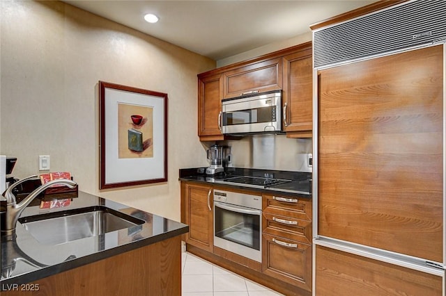 kitchen with light tile patterned floors, brown cabinetry, recessed lighting, a sink, and appliances with stainless steel finishes