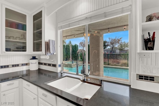 kitchen with a sink, white cabinets, backsplash, a wealth of natural light, and glass insert cabinets