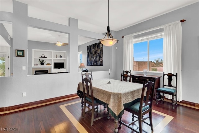 dining area featuring baseboards, a fireplace, dark wood finished floors, and built in features