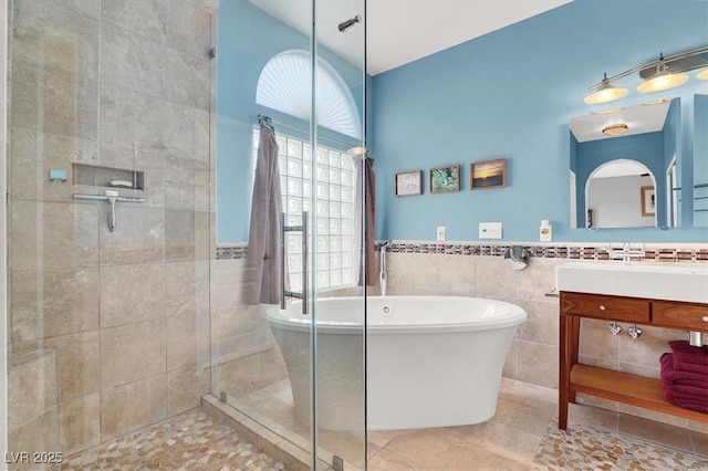 bathroom featuring tile walls, a soaking tub, a shower stall, vanity, and tile patterned flooring