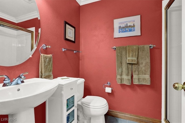 full bathroom with tile patterned flooring, toilet, a sink, a tile shower, and crown molding