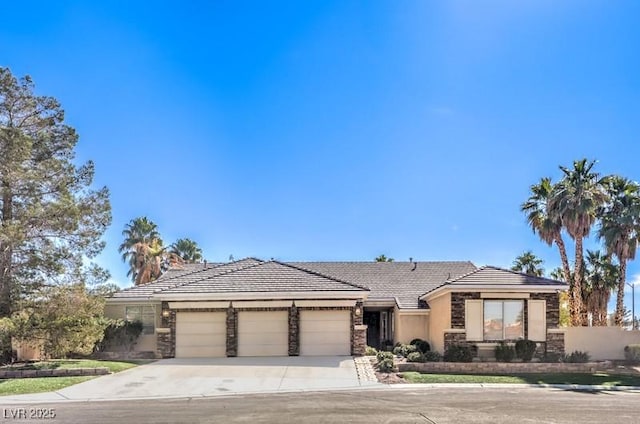 view of front of property with driveway, stone siding, a tile roof, an attached garage, and stucco siding