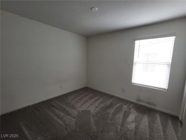 carpeted empty room featuring baseboards