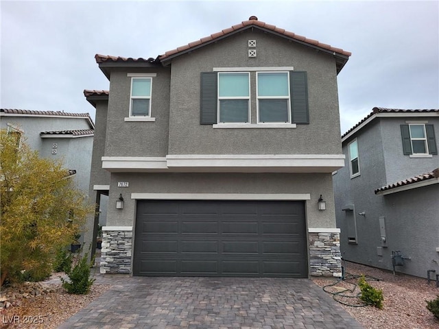 view of front of property with decorative driveway, stone siding, an attached garage, and stucco siding