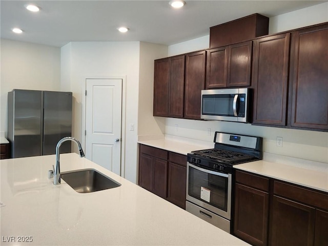 kitchen with appliances with stainless steel finishes, light countertops, dark brown cabinets, a sink, and recessed lighting