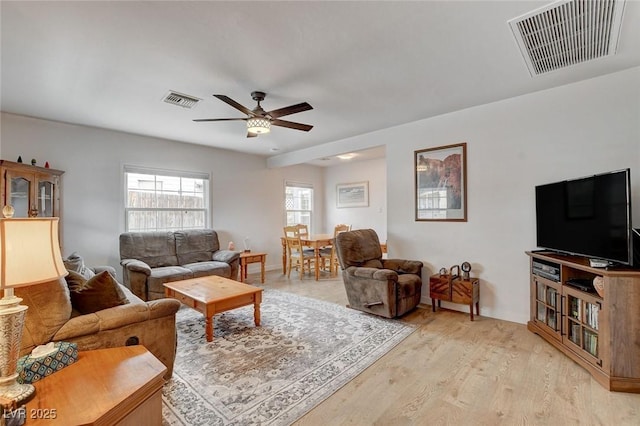 living area with light wood-style flooring, visible vents, and ceiling fan