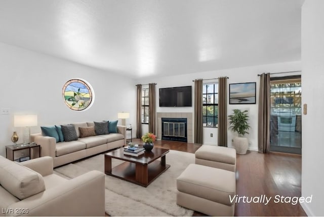 living area with a tile fireplace and wood finished floors