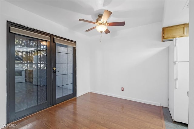 interior space featuring a ceiling fan, french doors, baseboards, and wood finished floors