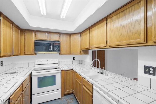 kitchen with black microwave, electric range, a sink, tile counters, and a tray ceiling