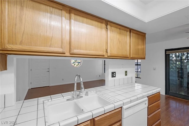 kitchen featuring tile countertops, dark wood-type flooring, white dishwasher, and a sink